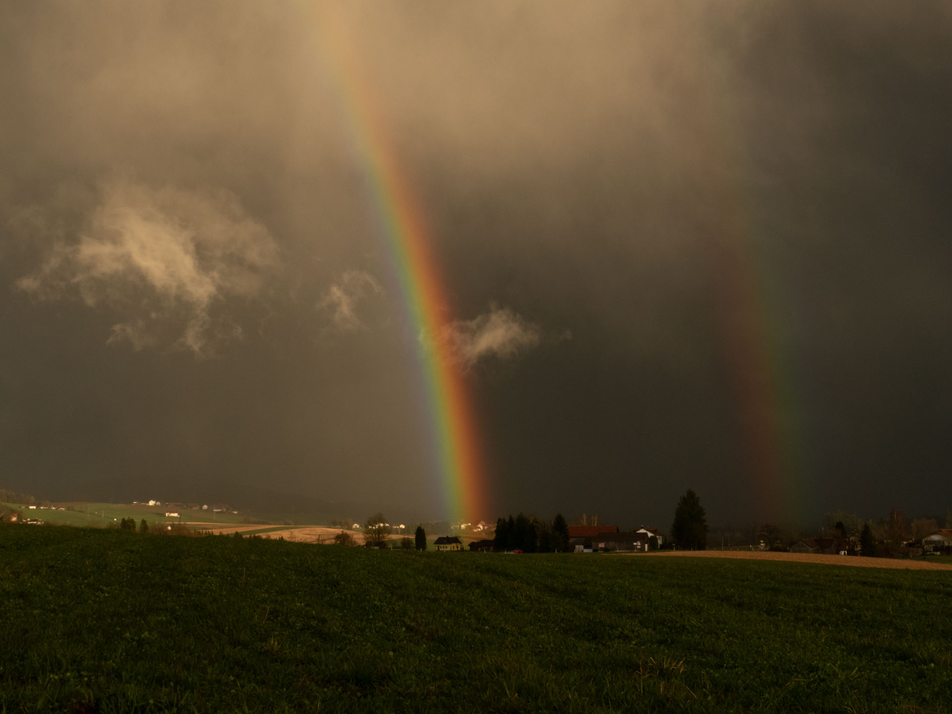 Regenbogen über einer weiten Landschaft, ein Bild für die Verbindung von Himmel und Erde.